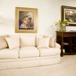 Photo of a living area at Towne Centre at Englewood showing a comfortable couch with a side floor lamp and bureau.